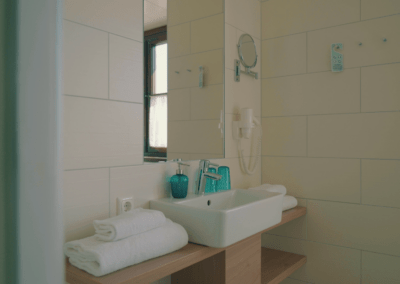 Badezimmer mit Waschbecken, Föhn, Spiegel und Handtüchern